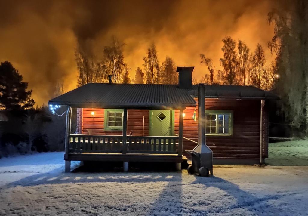 a log cabin with a fire in the background at Ekesberget Stugby Pippi Stuga in Ekshärad