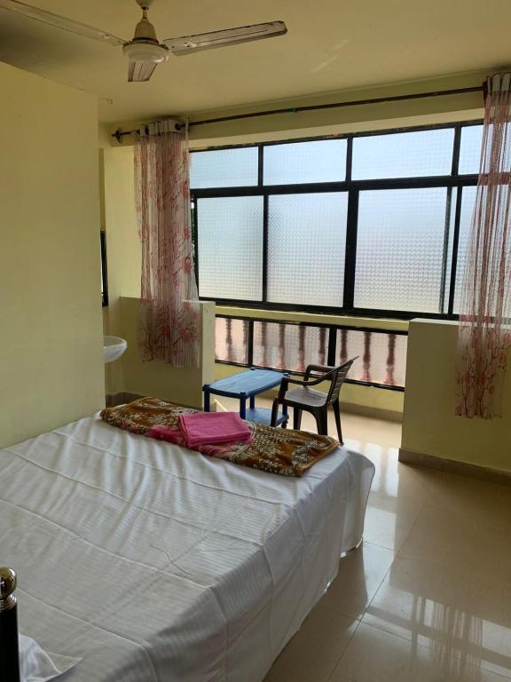a bedroom with a bed and a table and windows at water front guest house in Arambol