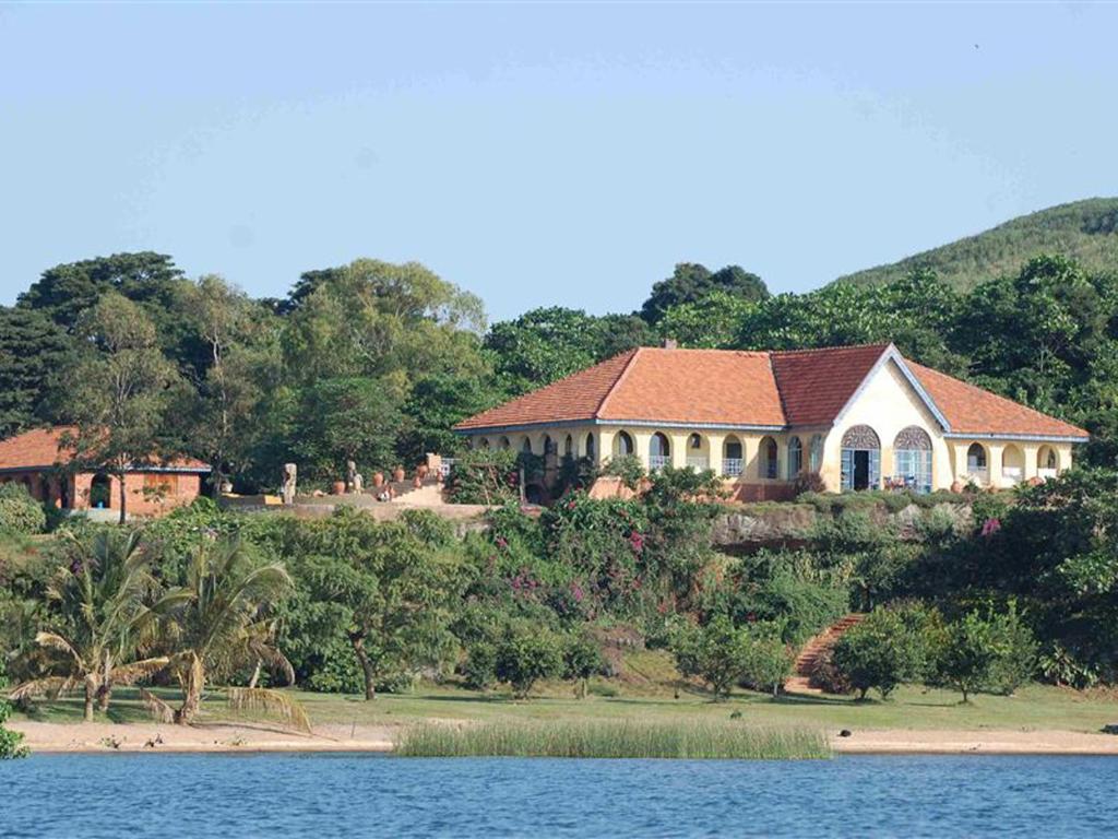 a house on a hill next to a body of water at One Minute South Villa in Bulago Island