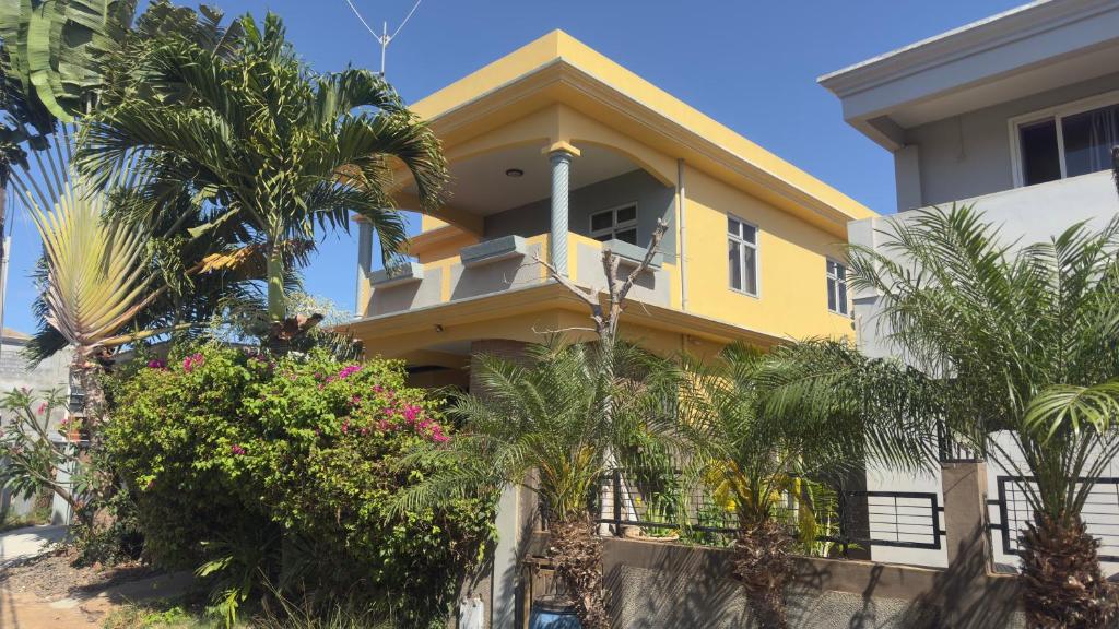 a yellow house with palm trees in front of it at Résidence Oak in Petite Rivière