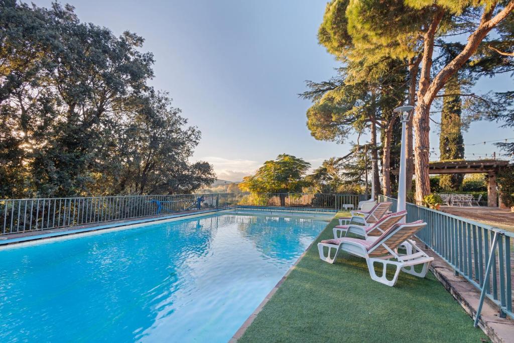 a swimming pool with two lounge chairs and trees at Tordera Village in Tordera