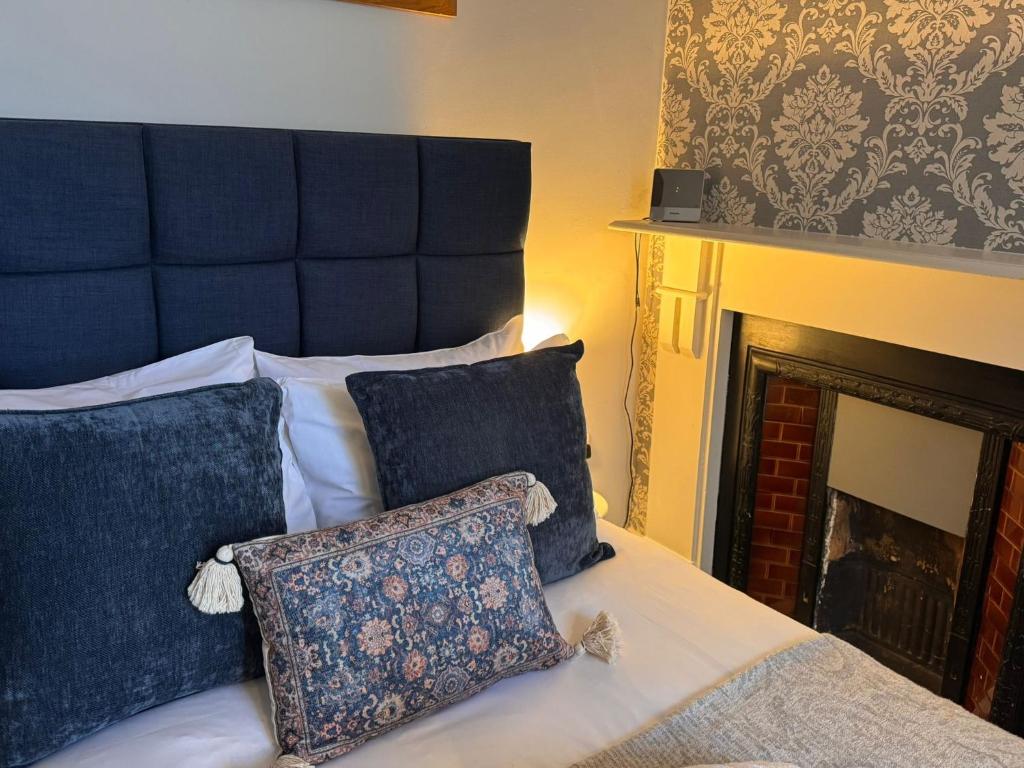una cama con cabecero y almohadas azules junto a una chimenea en Regency House, en Cambridge