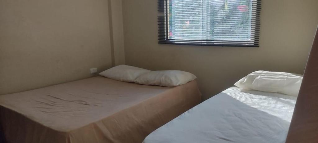 two beds in a small room with a window at Casa refúgio in Ibicoara