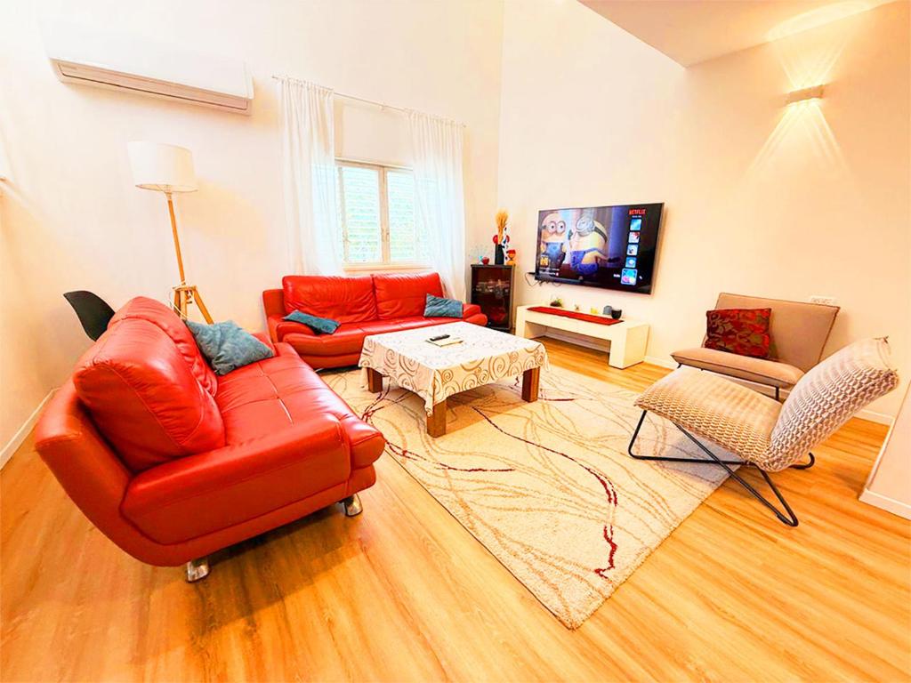 a living room with a red leather couch and chairs at Spacious 3BD Penthouse with Rooftop & Parking in Ra‘ananna