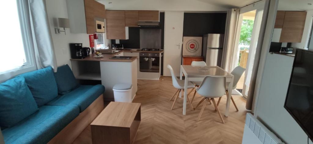 un salon avec un canapé bleu et une cuisine dans l'établissement DOMA Mobil home 3 chambres Litteau, à Litteau
