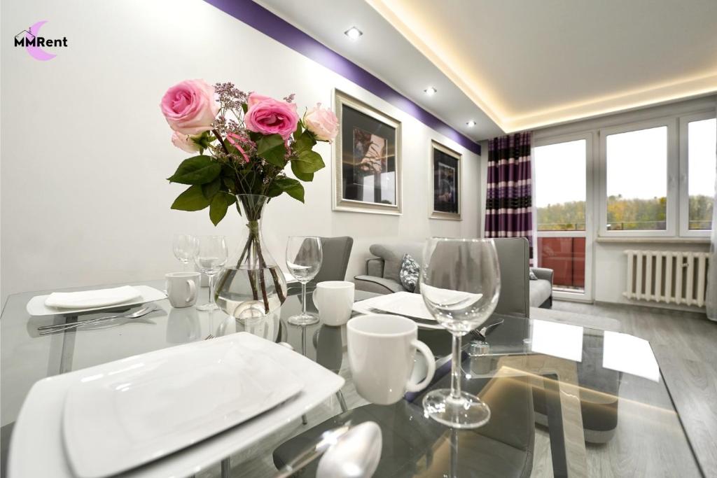 a dining room with a glass table with pink roses at MMRent Apartament CityLight in Gdańsk