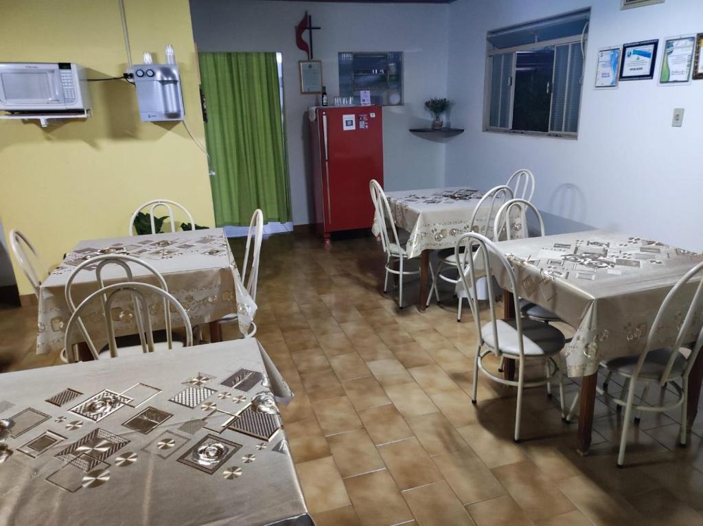 a room with tables and chairs and a red refrigerator at Pousada Rezende in Caldas Novas