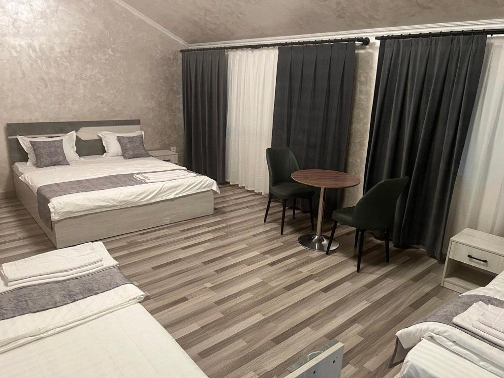 a bedroom with two beds and a table and chairs at Pearl House in Muruntau