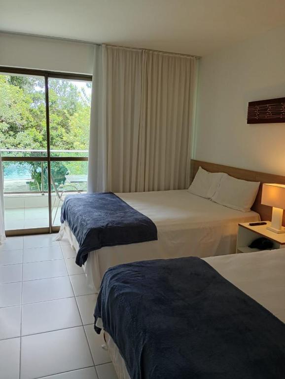 a hotel room with two beds and a window at RM Beach Paradise - Barra Iloa Residense in Barra de São Miguel