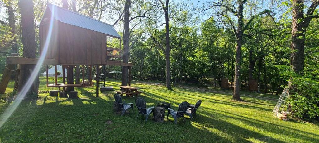 a group of chairs sitting in the grass at Tree House Glamping Destination near the Ozarks, with River Access for Swimming and Fishing in West Liberty