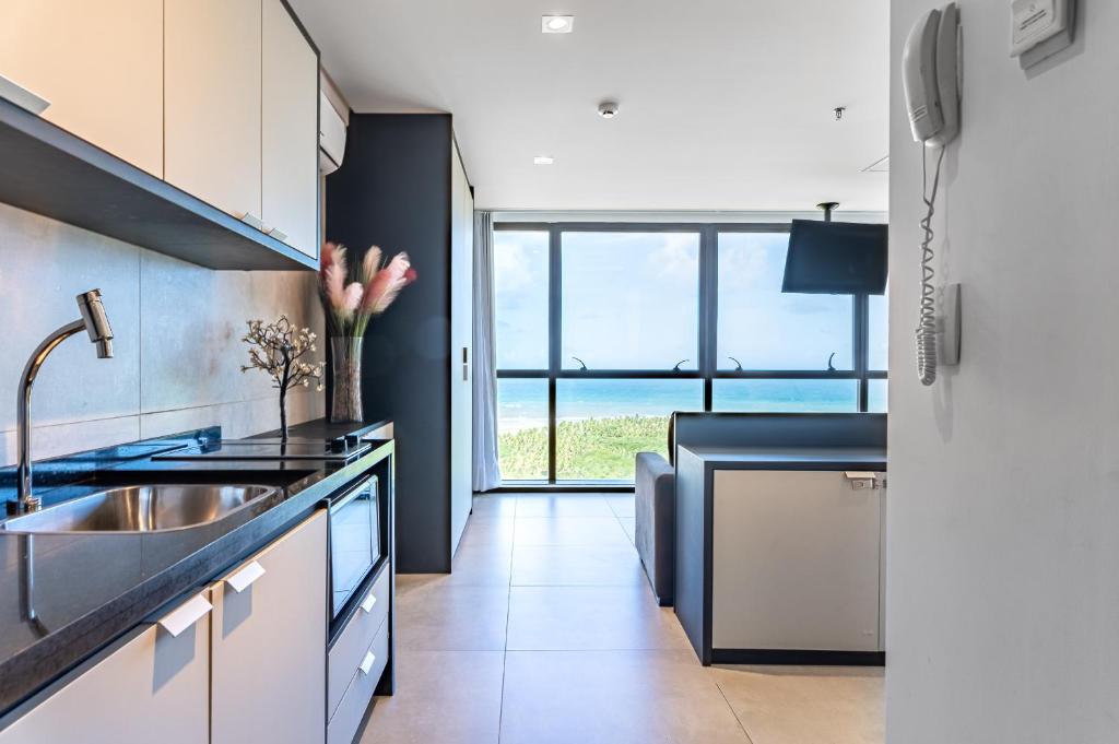 a kitchen with a sink and a large window at BHS Flat a beira mar 2203 in Recife
