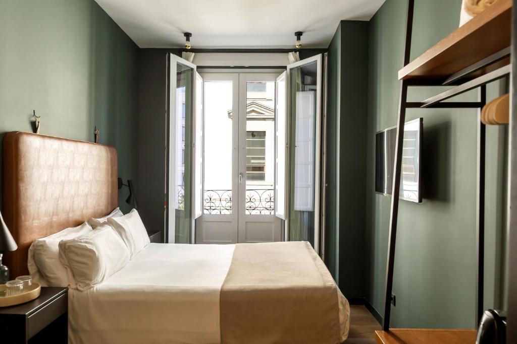 a bedroom with green walls and a bed and a window at Colectia Stays Atocha in Madrid