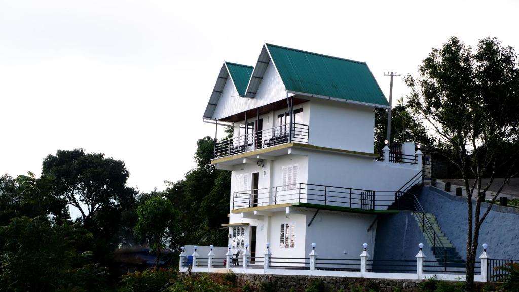 a white house with a green roof at Elora Homes in Vagamon