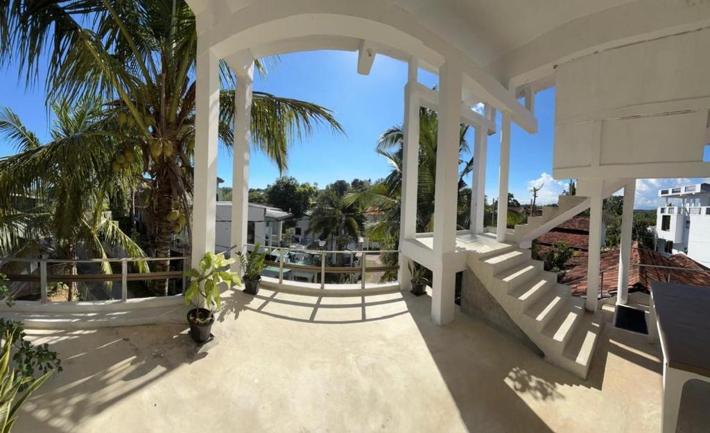 a large white house with a porch with palm trees at Villa Calton 32 Villa in Weligama Bay in Weligama