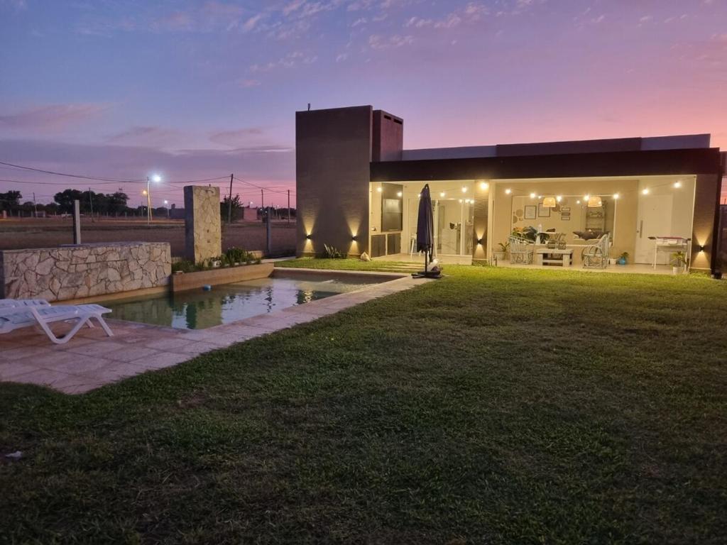 una casa con piscina en el patio por la noche en Quincho Sauco en Colonia Benitez, en Colonia Benítez