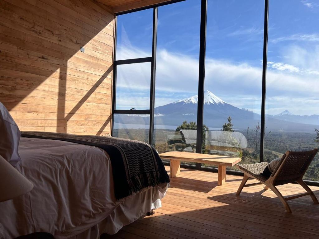 1 dormitorio con cama, mesa y montaña en Ampe Lodge, en Puerto Varas