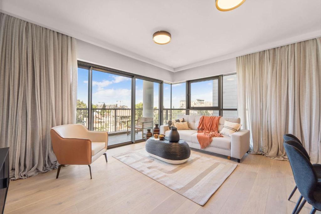 Una sala de estar con un sofá y una ventana grande. en Savyon View 2 Bdr By Isrentals, en El Muṣrāra