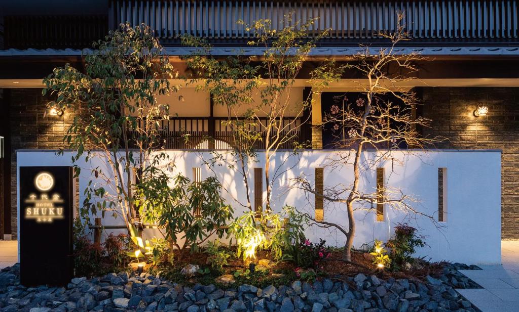 a building with trees and lights in front of it at Chiyokura HOTEL SHUKU Nagoya in Nagoya