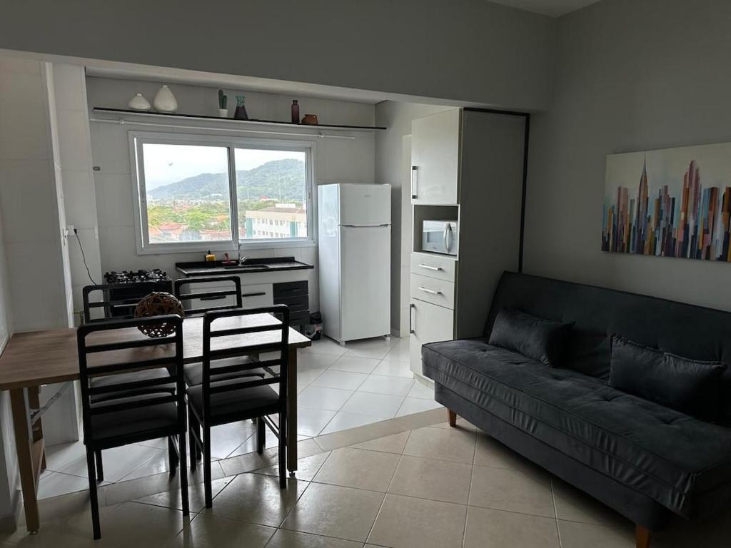 Una sala de estar con un sofá y una mesa y una cocina. en Frente ao Mar - Acorde Com o Barulho das Ondas apto 10, en Praia Grande