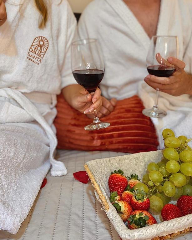 Dos personas sosteniendo copas de vino y un plato de fruta. en Loft p/ casal hidro, café, a/c e vista, en Santo Amaro da Imperatriz