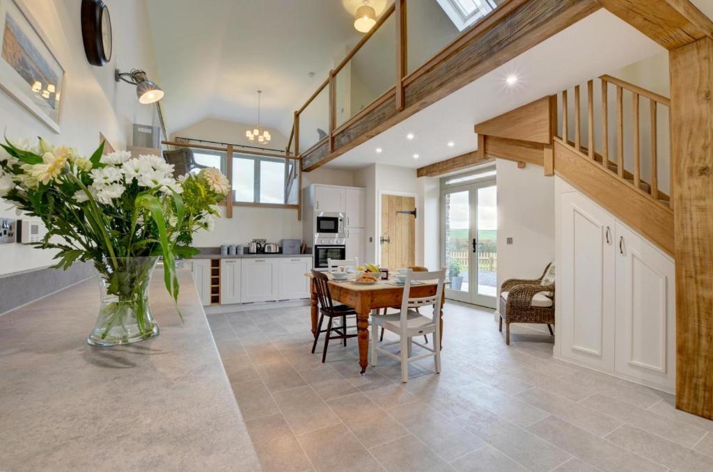 a kitchen and dining room with a table and a vase of flowers at Barton Barn in Bishops Nympton