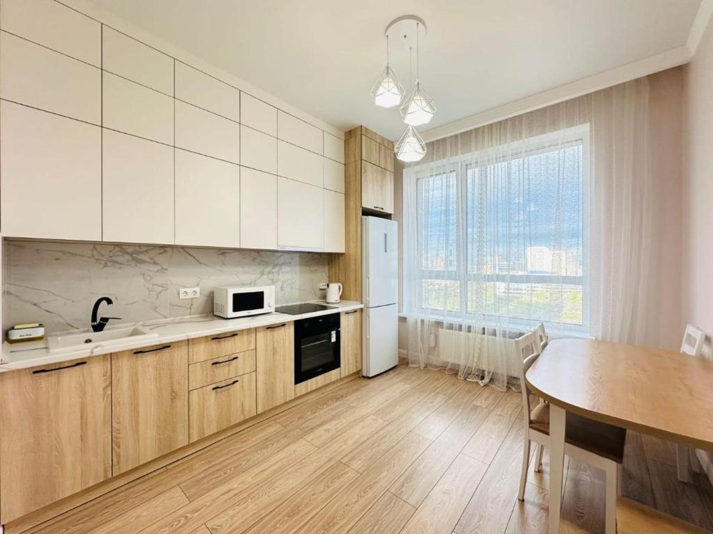 uma cozinha com armários brancos, uma mesa e uma sala de jantar em GRAND-TURAN Bussiness em Astana