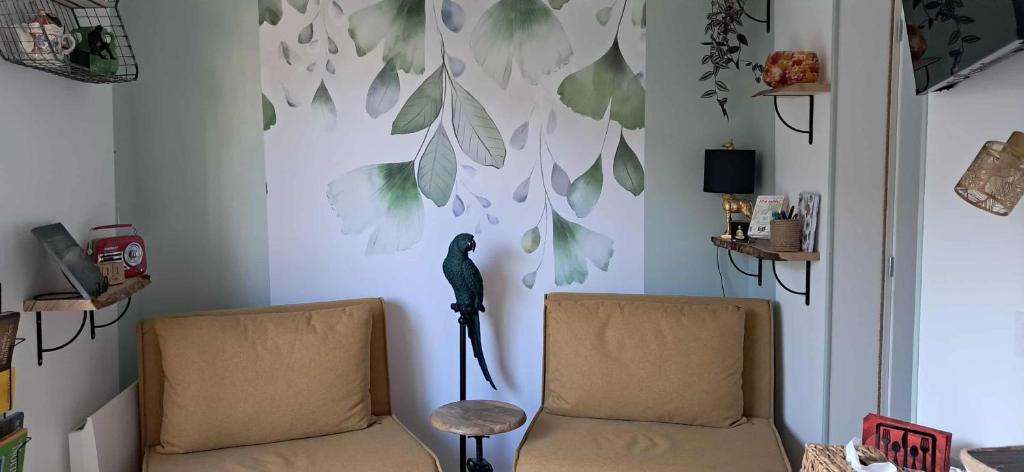 a room with two chairs and a wall with leaves at Comme à la maison in Ducey