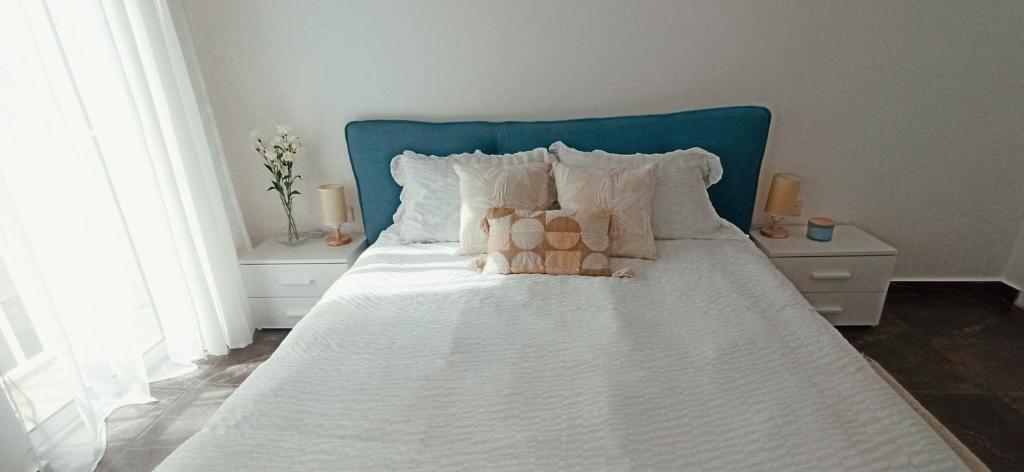 a white bed with white pillows and a blue headboard at Cozy penthouse with Citadel view near to Victoria in Sannat