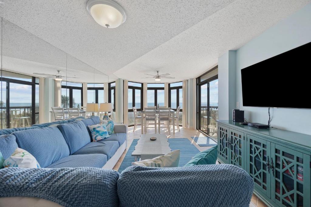 un salon avec un canapé bleu et une télévision à écran plat dans l'établissement Beautiful & Modern Updated Oceanfront Condo for 10! Sedgefield North 103, à Myrtle Beach