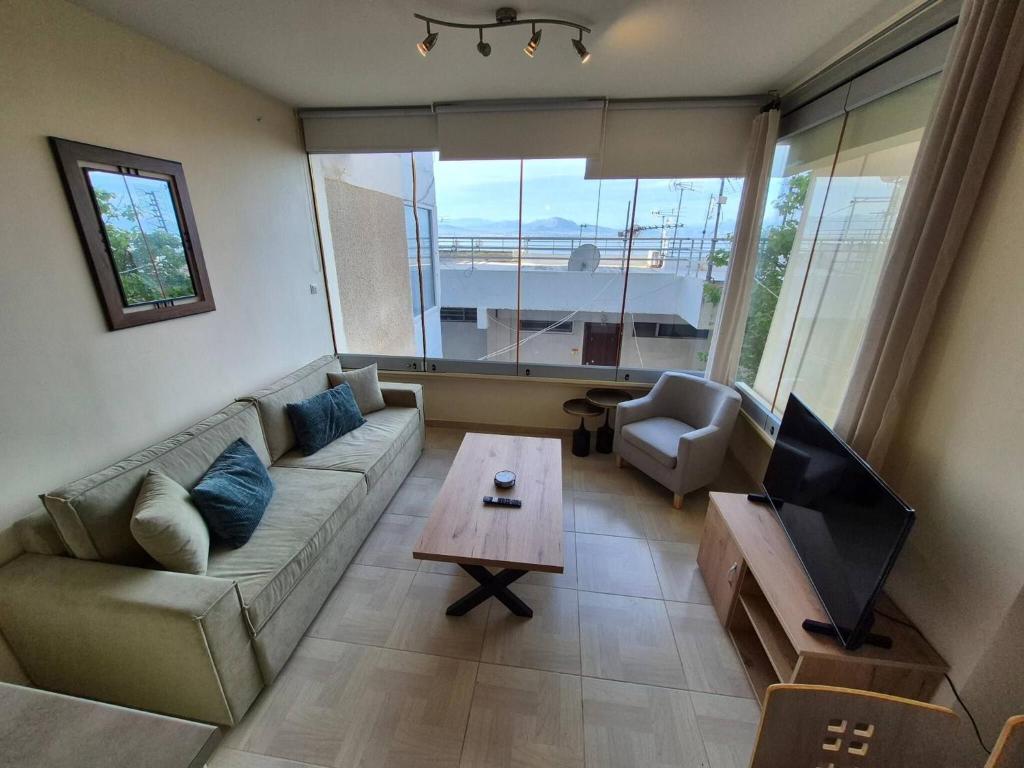 ルートラキにあるAtlas on the water - Loutrakiのソファ、テレビ、テーブルのあるリビングルーム