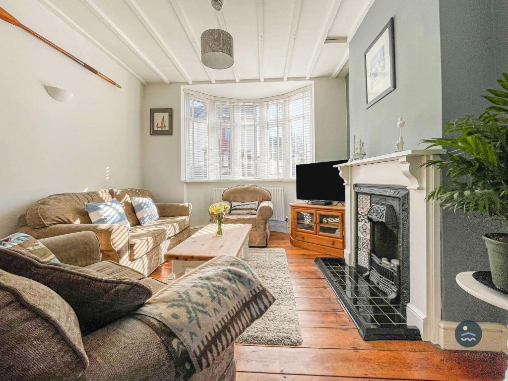 a living room with two couches and a fireplace at Harvest Moon - cottage close to harbour in Weymouth