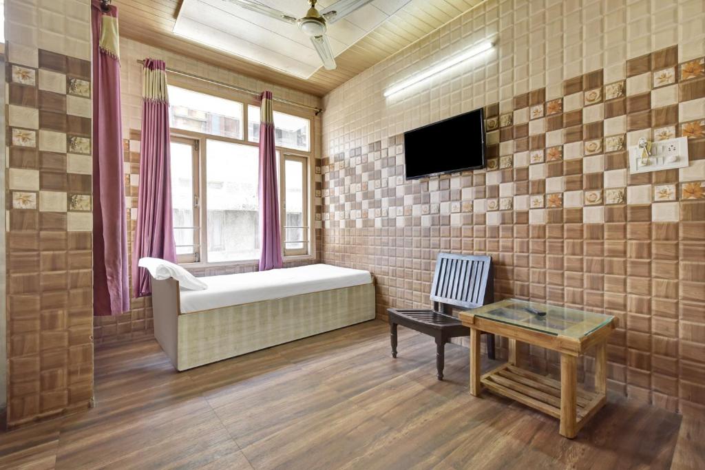 贾姆穆Hotel O Indira的一间设有床铺和墙上电视的房间