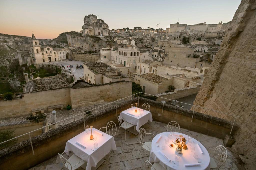 Dos mesas en un balcón con vista a una ciudad. en Sant'Angelo, Matera - Small Luxury Hotels, en Matera