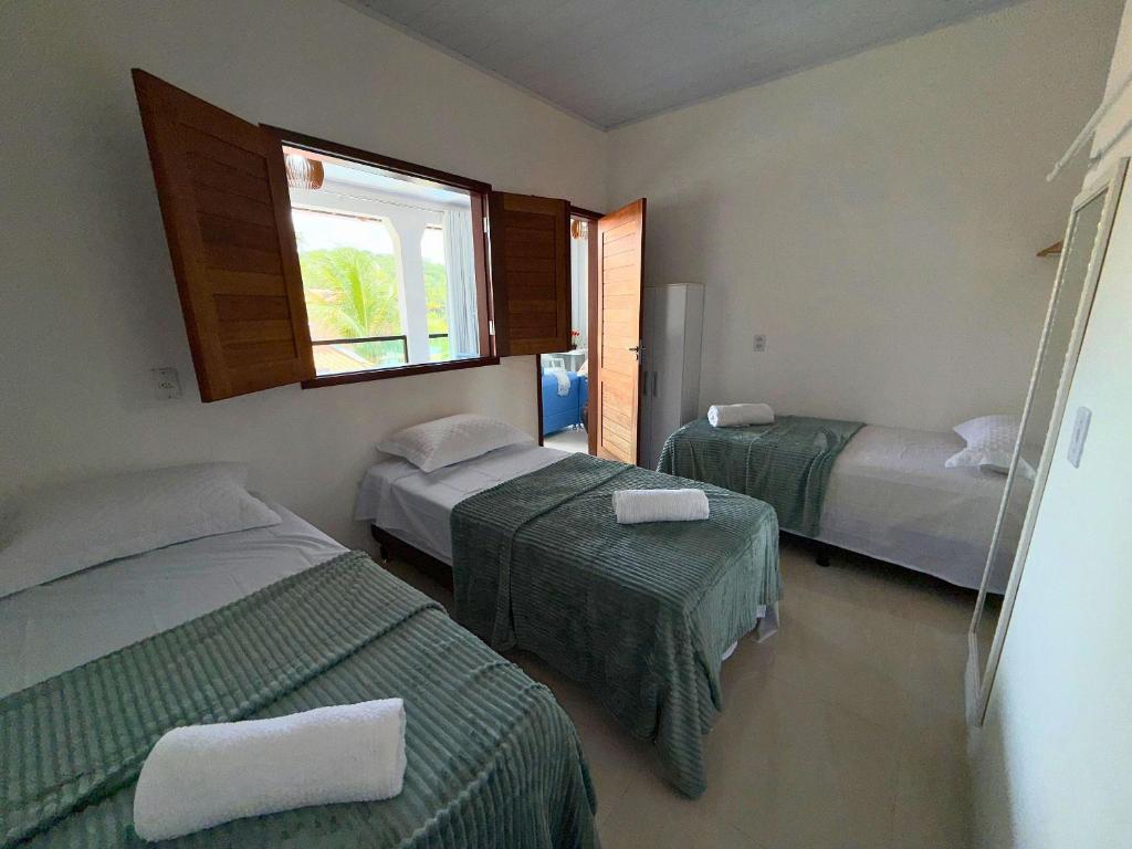 een hotelkamer met twee bedden en een raam bij MHV Milagres - Casa Lar do Marceneiro, Casa reservada e privativa a poucos metros da Praia do Marceneiro e da Capela in Passo de Camarajibe