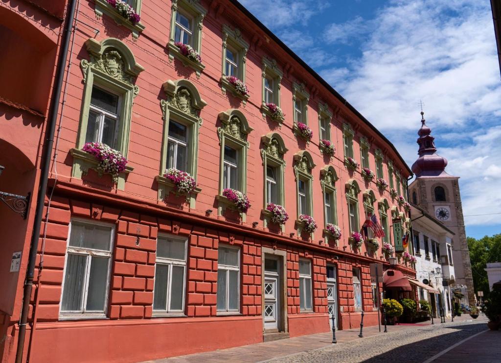 a red building with flower boxes on the side of it at Hotel Ptuj in Ptuj