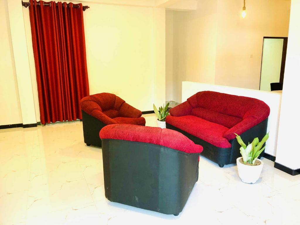 a living room with two chairs and a red couch at Umami Japanese House Tangalle in Tangalle