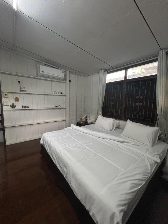 ein großes weißes Bett in einem Zimmer mit Fenster in der Unterkunft Wooden Friend House in Krabi