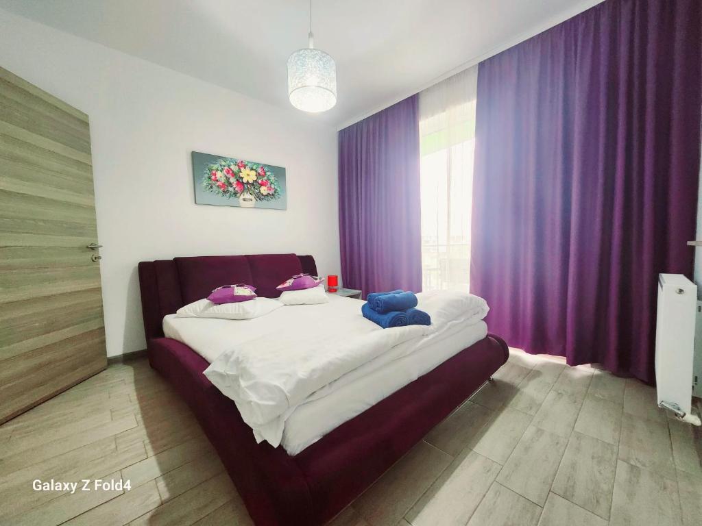 a bedroom with a large bed with purple curtains at Luxury ApartHotel Alezzi Spa Resort Piscina Incalzita in Mamaia Nord