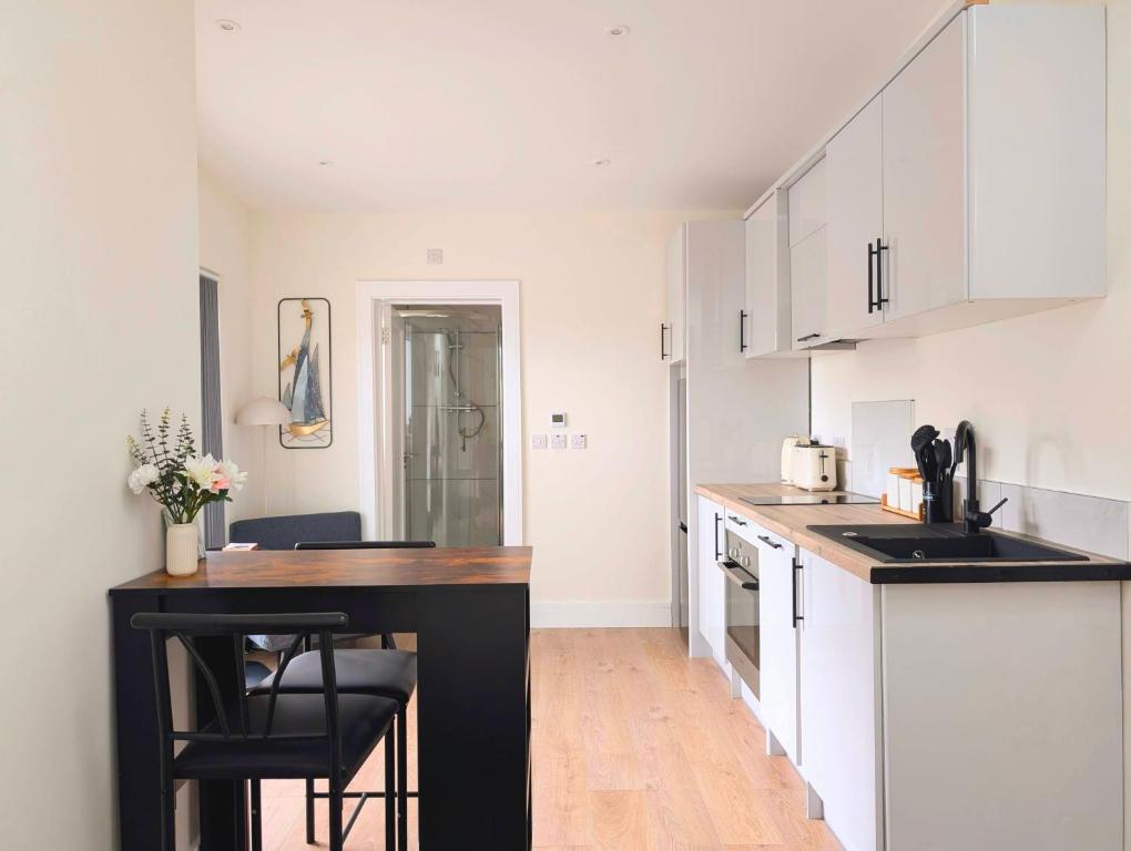 a kitchen with white cabinets and a black counter top at Foothills Haven - Private Garden Apartment near Luas & Trails in Dublin