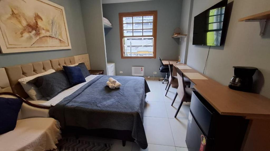 Un dormitorio con una cama con un osito de peluche encima. en Quarto Plus Gonzaga, en Santos