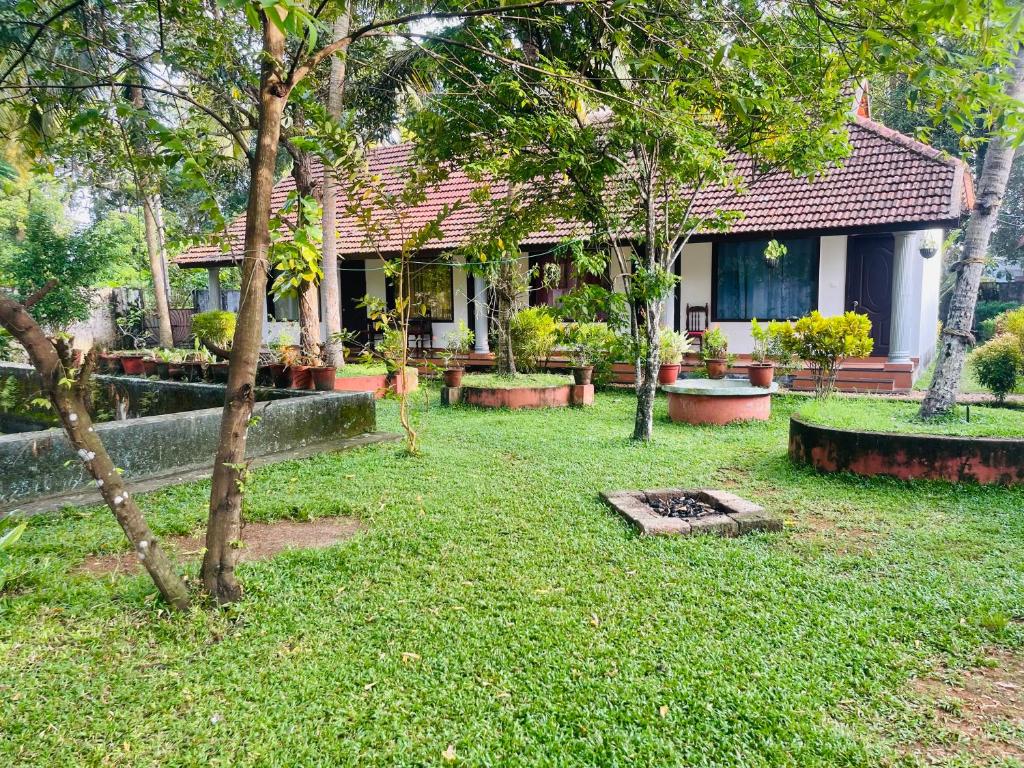 a house with a yard with trees in front of it at Hamlet Beach Villas Alleppey in Alleppey