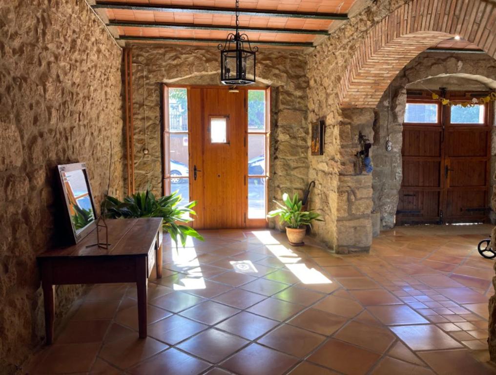 un couloir en pierre avec une porte en bois et une table dans l'établissement Cal Fuliola, à Vallfogona de Balaguer