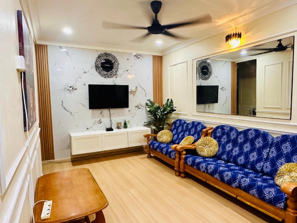 a living room with a blue couch and a tv at D Erin Homestay in Banting