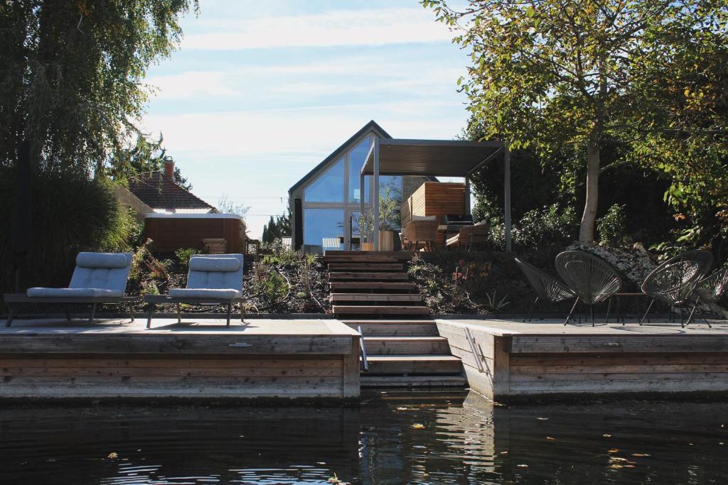 una casa con dos sillas y un cuerpo de agua en Luxus Vendégház a Szigetköz szívében, en Dunasziget