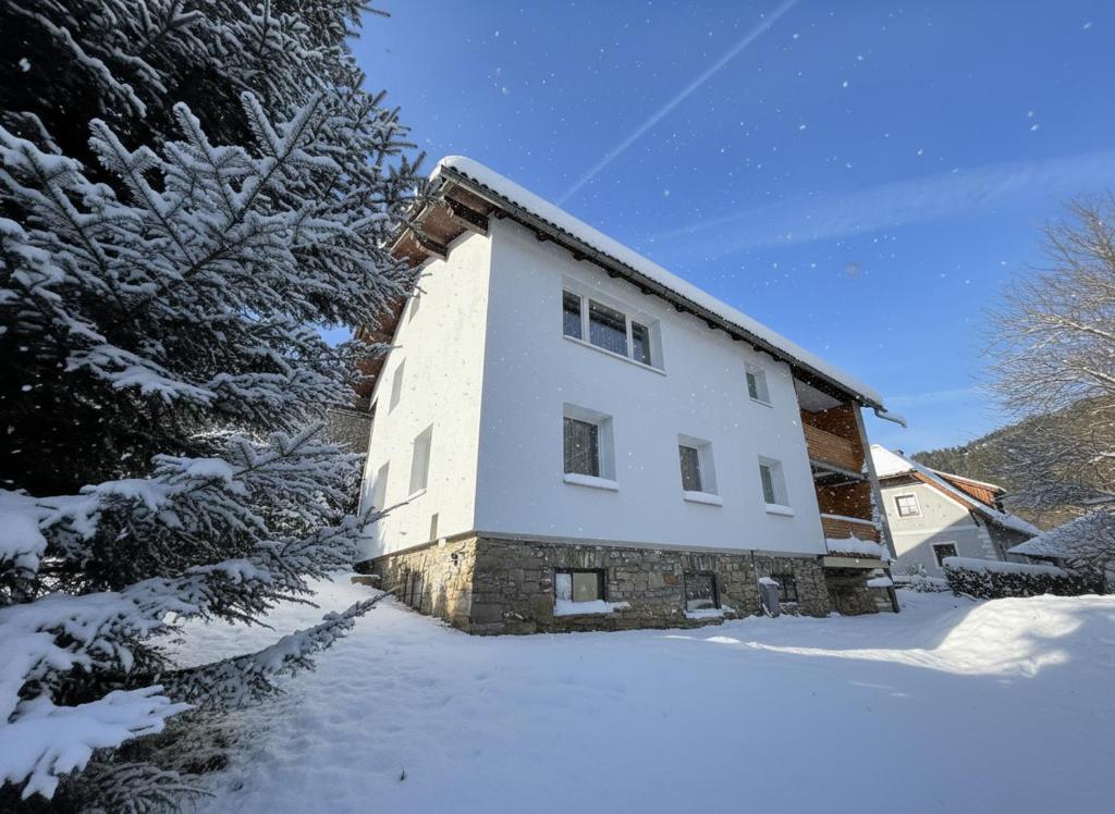 a white house with snow on the ground at White Pearl Apartment in Murau