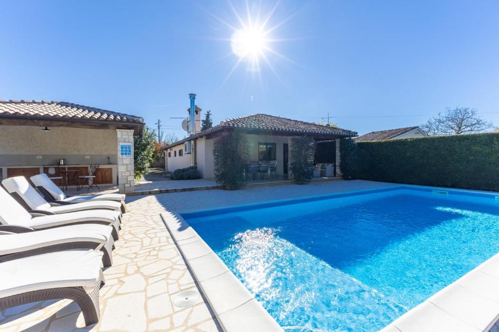 a swimming pool with lounge chairs in a backyard at Villa Mainenti in Višnjan