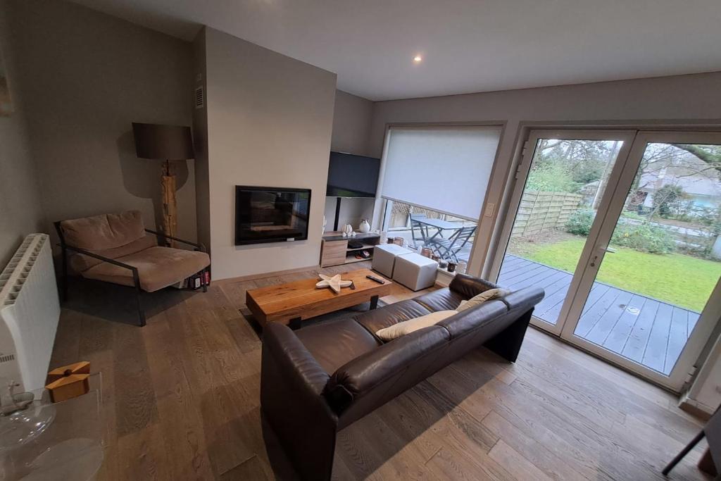 a living room with a leather couch and a table at Villa touquettoise near the sea in Le Touquet-Paris-Plage