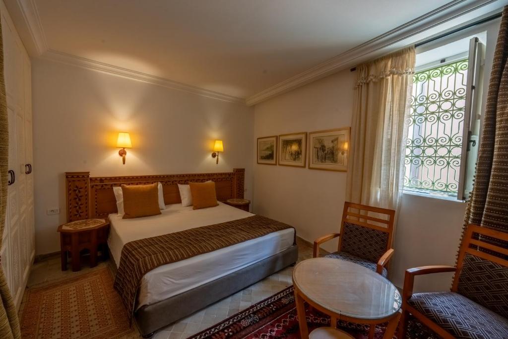 ケルアンにあるDar Dhiafa Paul Klee Kairouanのベッドと窓のあるホテルの部屋