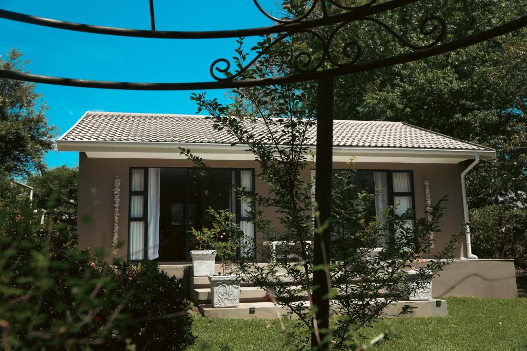 een klein huis in een tuin met bomen bij Two on Bramble in Hilton