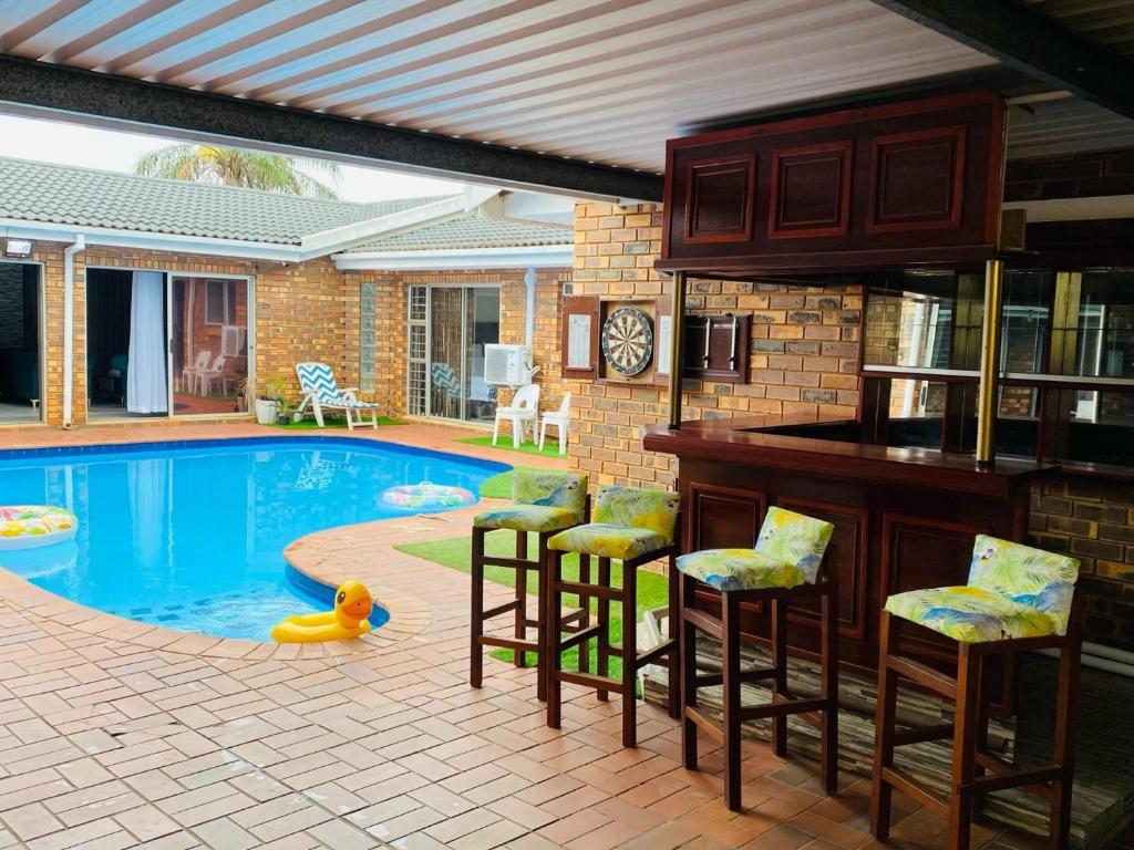 een zwembad met barkrukken en een keuken en een huis bij Tranquil Retreat in Durban